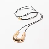 Collar con dije dorado en forma de U invertida, colgando de un cordón negro.