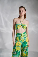 Top strapless con estampado floral en tonos verde y amarillo, con tirantes finos al cuello y detalle de nudo en el centro del busto.