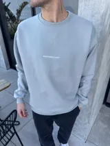 Buzo de algodón con calce oversize, cuello redondo y puños acanalados. Presenta un bordado minimalista con el logo de la marca en el centro del pecho.