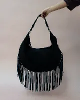 Cartera de hombro tipo hobo en color negro, confeccionada en gamuza con diseño de flecos largos en todo el contorno inferior. Presenta un asa trenzada con detalles artesanales y cierre superior.