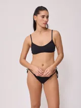 Top de bikini deportivo color negro, con escote redondo y breteles finos ajustables. Presenta el logo de la marca estampado en blanco en la parte inferior izquierda.