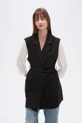 Chaleco largo de corte recto y diseño abierto, con solapas clásicas y bolsillos laterales. Confeccionado en poliéster, presenta una caída fluida y un estilo versátil ideal para superposiciones.