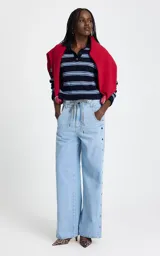 Sweater de punto con diseño a rayas horizontales en tonos azul marino y celeste. Presenta cuello polo estructurado, escote con abertura y botones, y mangas largas con puños ajustados.