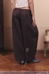 Pantalón de gabardina impermeable color marrón chocolate, con silueta amplia y relajada. Presenta cintura elastizada con pinzas delanteras que aportan volumen y movimiento a la prenda.