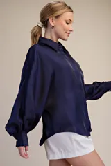 Blusa de satén azul marino con cuello camisero y mangas largas voluminosas con puños abotonados.