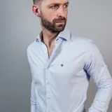 Camisa negra de algodón con cuello clásico, manga larga y cierre frontal con botones. Presenta un logo bordado en el pecho. Corte entallado.