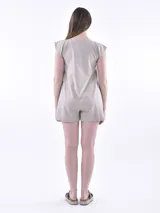 Monoprenda (romper) de color rojo, sin mangas, con cuello redondo y cierre frontal de botones. Presenta bolsillos delanteros a la altura de la cadera y un corte holgado.