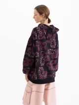 Buzo tipo hoodie oversize de tela de punto frizada, con estampa full print en tonos negro y bordó. Presenta capucha con cordones ajustables, puños y cintura con terminaciones en ribb.