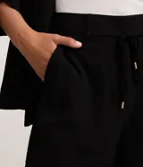 Short de corte recto y cintura alta, confeccionado en tejido airflow con textura arrugada. Presenta trabillas, lazo ajustable en la cintura, cierre tradicional y bolsillos laterales tipo carpintero.