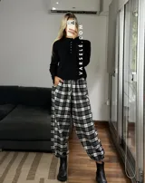 Pantalón estilo balloon de tela escocesa, con cintura elástica y cordón ajustable. Presenta un diseño holgado con puños elásticos en los tobillos.