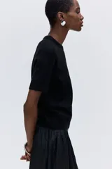 Buzo de punto fino suave con cuello redondo y mangas cortas. Presenta terminaciones acanaladas en el cuello, los puños y el bajo.