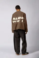 Buzo oversize de algodón rústico de alto gramaje, color beige, con diseño boxy, bordes con terminación cruda y estampa frontal con el texto VCP.