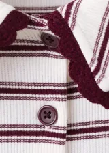 Polo de manga corta a rayas con cuello estilo polo en color borravino y cierre frontal de botones. Cuenta con detalles festoneados en el cuello y los puños.