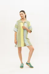 Vestido corto tejido en algodón con lurex, con cuello tipo camisa, abotonado al frente y mangas cortas.