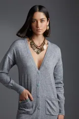 Vestido tipo cardigan gris con botones, escote en V, bolsillos frontales y mangas largas.