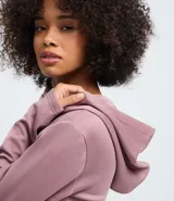 Campera corta con capucha fija, cierre frontal con cremallera y mangas largas, confeccionada en tejido modal con acabado satinado.