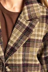 Tapado de corte recto y largo medio, confeccionado en tela de poliéster con estampado de cuadros en tonos verdes, marrones y violetas. Presenta solapas clásicas, cierre frontal y diseño estructurado.