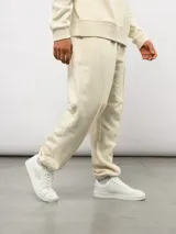 Pantalón de felpa color crema, con corte relajado, costuras verticales en la parte delantera y etiqueta con el logo de Umbro.