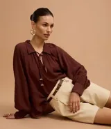 Short de mujer color beige claro, de cintura alta y corte holgado, con pliegues frontales y cierre tradicional. Incluye un cinturón fino de material sintético marrón.