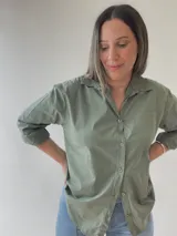 Camisa celeste de corte holgado, con cuello clásico, cierre frontal con botones, bolsillo en el pecho y mangas largas con puños abotonados.