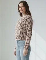 Buzo de lana con diseño de animal print en tonos rosado y marrón oscuro. Es de corte crop, manga larga amplia y cuello redondo.