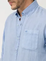 Camisa celeste de lino con cuello camisero, manga larga, cierre con botones y bolsillo en el pecho.