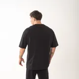 Remera de algodón premium con corte oversize y diseño unisex. Presenta bordado frontal con la palabra GAINS y bordado en la espalda con la palabra RESILIENCE.