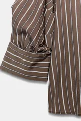 Camisa de cuello solapa con estampado de rayas verticales en tonos marrón y blanco. Presenta mangas abullonadas por debajo del codo con puños definidos y cierre frontal con botones.
