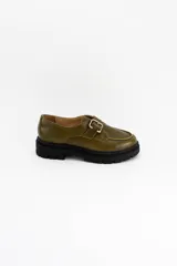 Mocasines de cuero color verde oliva con suela track negra de plataforma. Presentan una tira decorativa sobre el empeine con hebilla metálica dorada ajustable en el lateral.