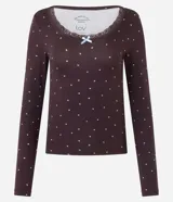 Blusa de pijama de manga larga color bordó con estampado de pequeños corazones blancos. Presenta escote en U con detalle de encaje y un pequeño moño celeste en el centro.