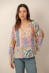 Blusa de manga larga con diseño patchwork multicolor que combina estampados florales, paisley y geométricos, con escote en V y mangas abullonadas.