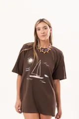 Remerón de algodón color marrón, de corte oversize y largo extendido, con estampa frontal temática de velero y mar.
