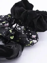 Pack de tres coleros para el pelo, uno de terciopelo negro, uno de tela negra con estampado de flores blancas y verdes, y uno de tela lisa negra.