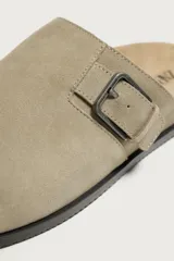 Zueco de piel con acabado serraje en color beige, punta redonda, plantilla anatómica de corcho y detalle de hebilla metálica lateral.