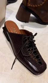 Zapatos destalonados de cuero en combinación marrón y negro con textura de cocodrilo, cordones negros, puntera cuadrada y taco geométrico de madera.