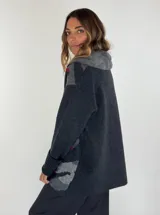 Saco de lana color verde militar con estampado abstracto en tonos verde oliva y detalles bordados en rojo. Tiene cuello solapa, cierre frontal con botones de madera y puños acanalados.