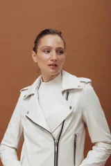 Chaqueta tipo biker de cuero negro con cierre frontal asimétrico, solapas con broches metálicos, bolsillos laterales con cierre y detalles de costuras acolchadas en la parte inferior.