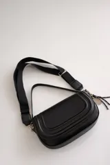 Cartera bandolera de tamaño compacto en color camel, con diseño estructurado y solapa frontal. Incluye doble asa: una corta fija de cuero sintético y una correa larga estilo sport regulable. Cuenta con cierre de cremallera y broche imantado, además de un detalle de llavero colgante.