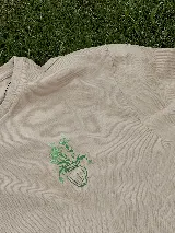 Remera blanca de algodón con estampa de un jarrón con flores en color verde.