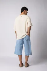 Remera de hombre, color crema, con cuello amplio y corte oversize. El tejido es liviano y texturado, similar al lino.