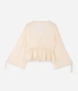 Blusa de viscosa texturada color marfil, con escote en V pronunciado, lazo frontal y corte estilo túnica. Presenta mangas largas abullonadas con puños ajustables mediante tiras y detalles de encaje en el escote, la cintura fruncida y el ruedo.