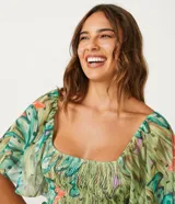 Blusa cropped de tul con estampado de bananas, escote cuadrado, mangas cortas amplias, detalle de látex en el cuerpo y volantes en el bajo.