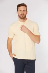 Remera polo lisa color amarillo pastel, confeccionada en piqué Oxford, con cuello en rib y botones personalizados.