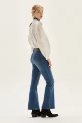 Jean de mezclilla azul de tiro medio, con silueta ligeramente acampanada desde la rodilla.