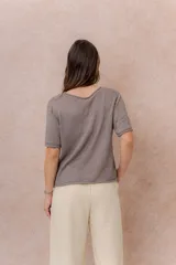 Buzo liviano de punto color blanco, de manga corta, con escote redondo y terminaciones con bordes enrollados.