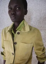 Chaqueta corta de piel de ante color verde, con diseño recto, cuello camisero, manga larga, dos bolsillos de parche en la parte delantera y cierre frontal con botones.