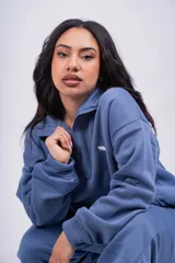 Buzo negro con cierre de media cremallera, cuello alto y logo bordado en el pecho.