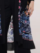 Cardigan tipo kimono largo de tul blanco semitransparente, con frente abierto y mangas largas. Presenta vistosos bordados florales multicolor en mangas, dobladillo y laterales.