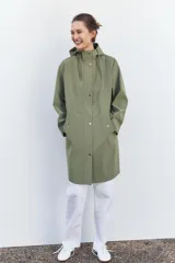 Chubasquero verde militar de cuello subido con capucha ajustable con cordones. Tiene manga larga, bolsillos delanteros con solapa y botón a presión oculto, y cierre frontal con cremallera oculta y botones a presión.