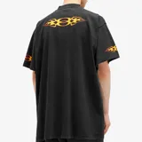 Camiseta negra de corte oversize con estampado de llamas en el pecho y en las mangas. Presenta el logo de la marca en el centro del diseño frontal.